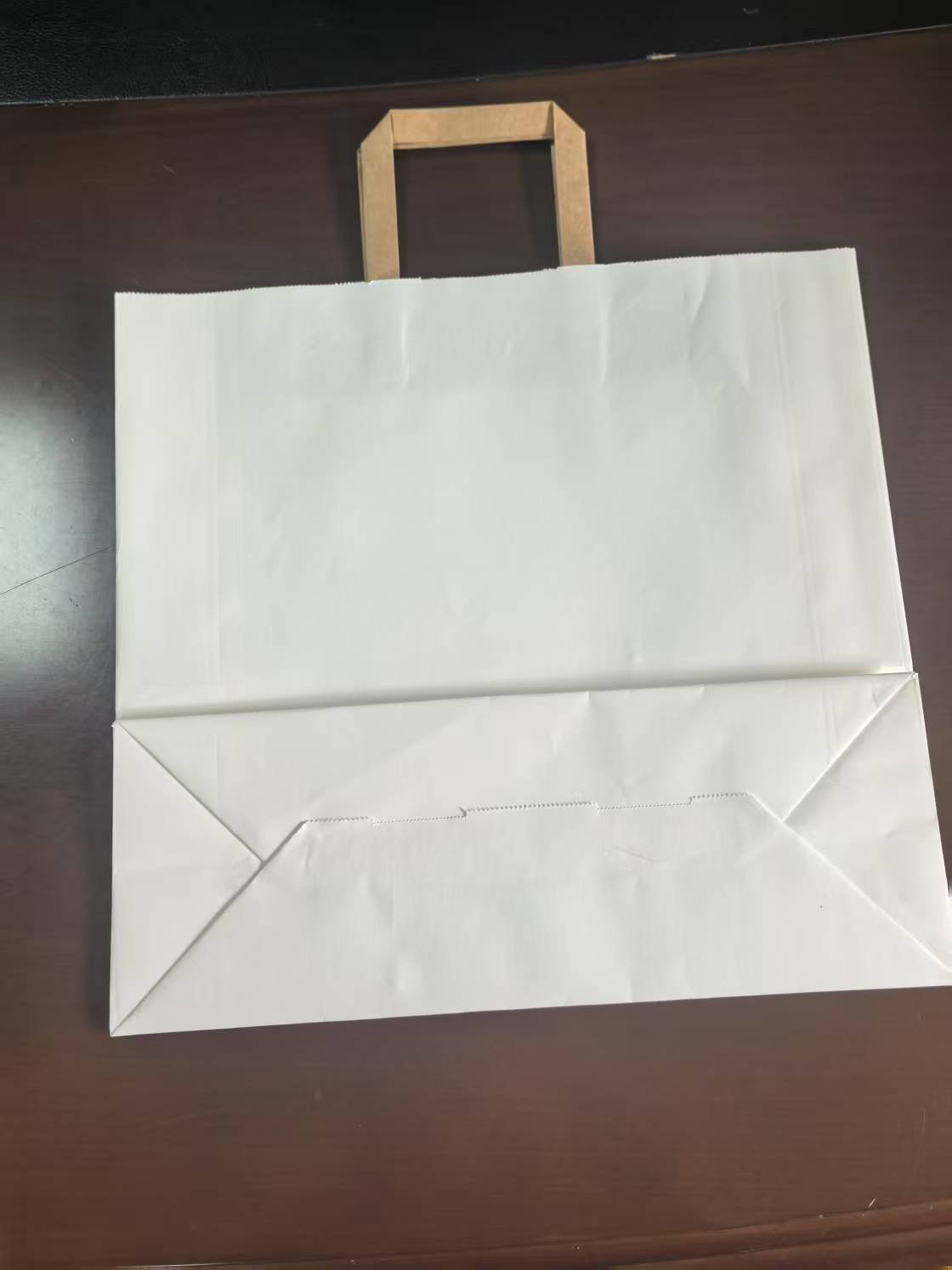 Bottom folding and pasting detail of white paper bag with flat handle produced by fully automatic square bottom paper bag machine