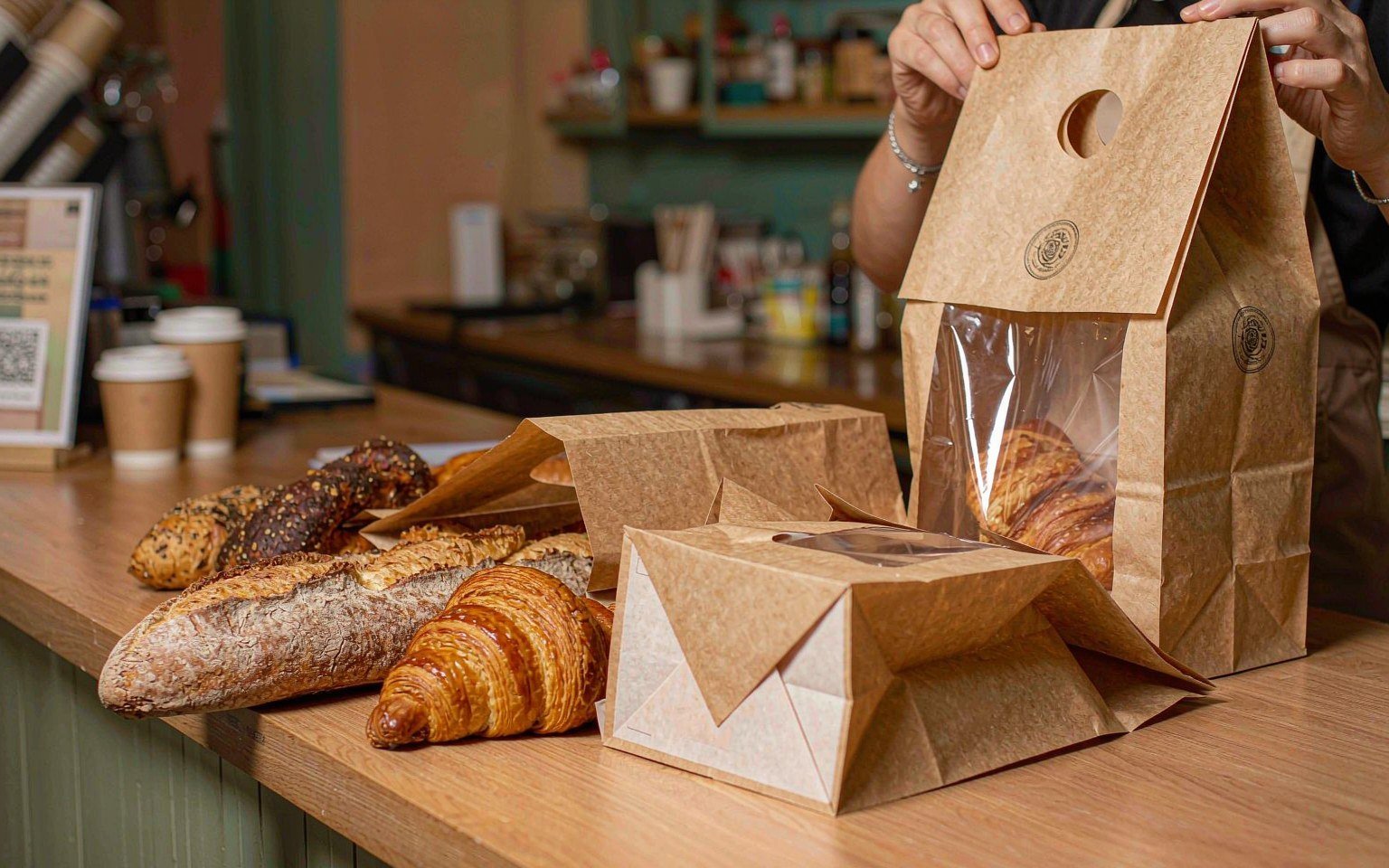 Bakery counter in a West African city placing fresh bread into kraft paper V-bottom and window bags instead of plastic